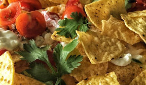 Plate of nachos with parsley tomatos and toppings.