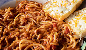 Close up view of spaghetti with meat sauce and cheese bread.